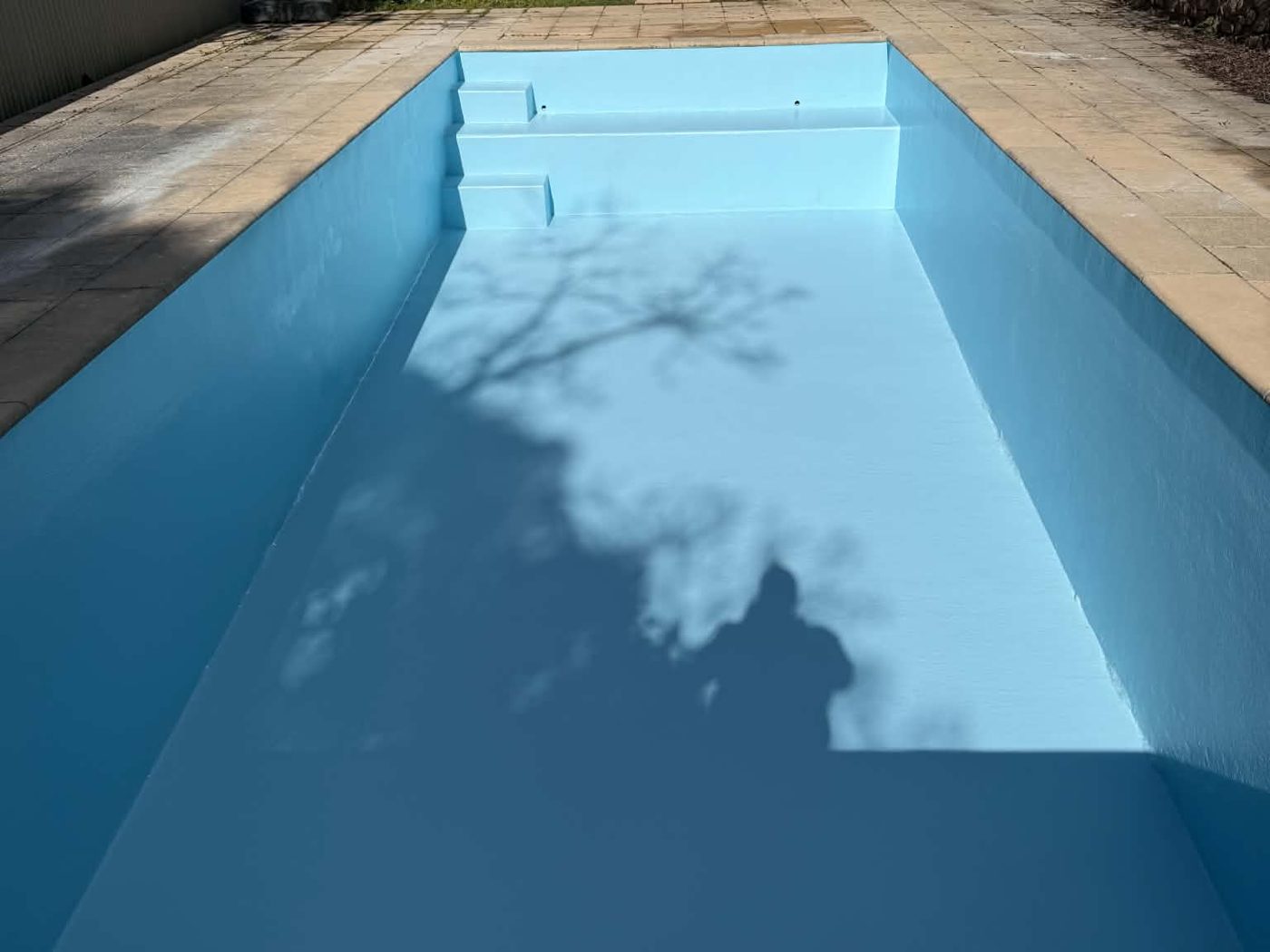 Oblong concrete pool in Eltham resurfaced in light blue fibreglass, before filling