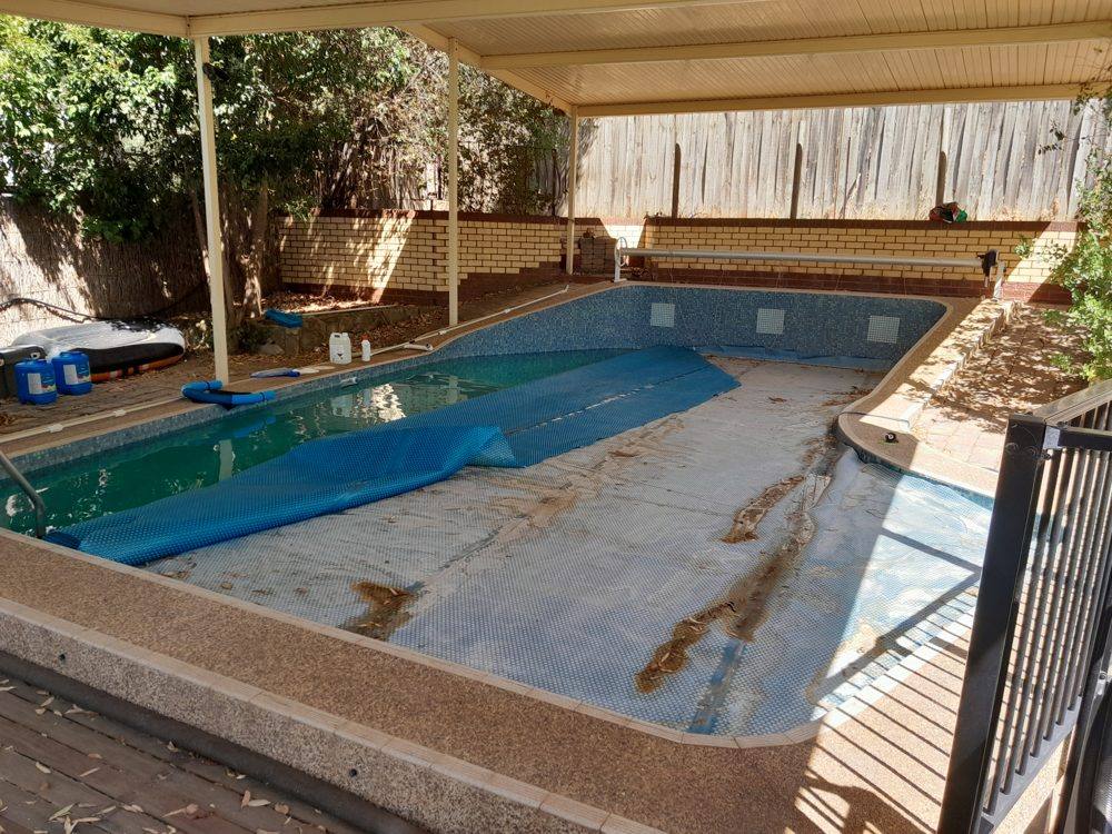 Drained marblesheen pool with stained, worn surface before resurfacing