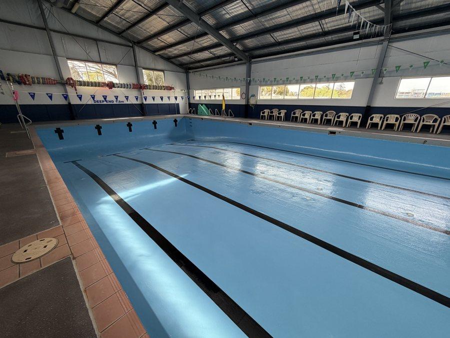 Indoor commercial lap pool resurfaced with dark lane lines, before filling