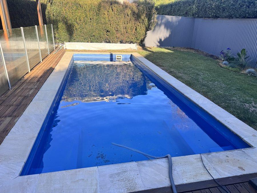 Long rectangular pool resurfaced in deep blue, filling