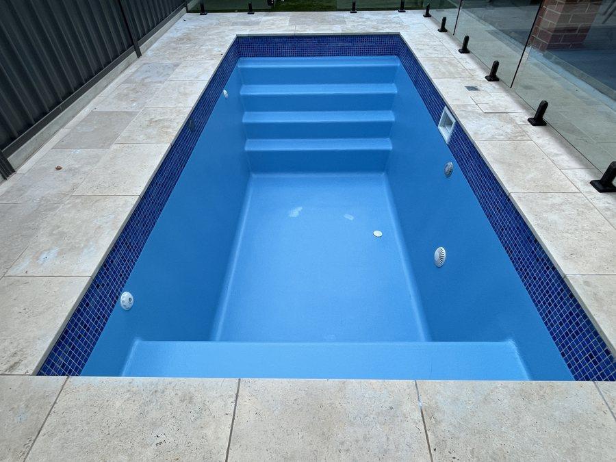 Pool resurfaced in blue with built-in steps and dark blue waterline tiles