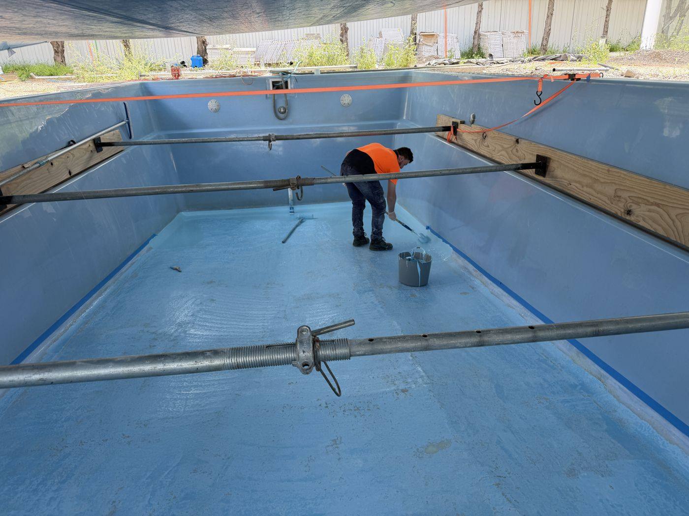 Crew member working inside a pool braced with steel props while it is empty